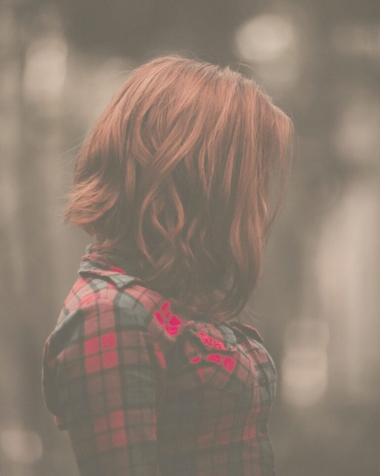 赤みのあるブラウンの、あご下の長さのボブ。チェックのシャツを着た女性の後ろ姿